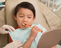 Child brushing teeth in dental chair