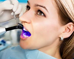 young woman getting dental bonding hardened with curing light 