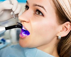 young woman getting dental bonding hardened with curing light