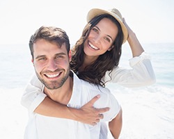 young man and woman smiling on the beach 
