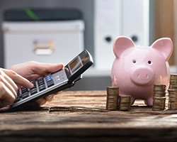Calculator is operated near piggy bank