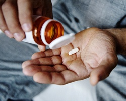 Man holding painkiller and prescription bottle