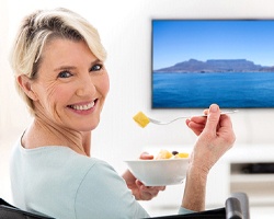 Woman smiling while eating bowl of fruit