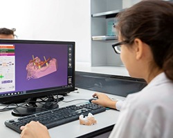Person using computer to design a dental prosthetic