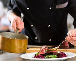 A chef spooning sauce onto a steak.