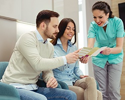 dental team member showing a pamphlet to two patients 