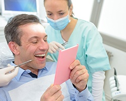 patient looking at his new smile in the mirror 