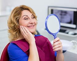 woman looking at her new smile in the mirror 