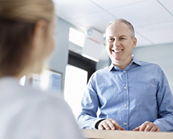 A man speaking with a dental employee.