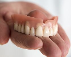 Hand holding a full denture