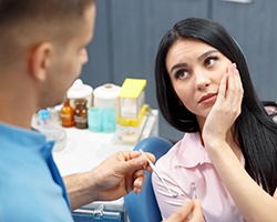 A young woman in pain listening to a dentist.