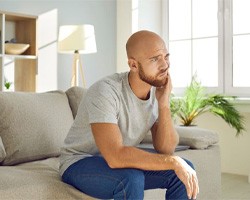 Man sitting on couch, struggling with toothache