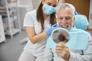 a man admiring his new dental implants at the dentist